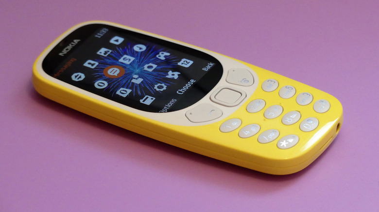 A close up of the Nokia 3310 feature phone on a pink background