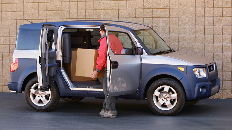 Front 3/4 view of 2003 Honda Element, showing right-side doors open and packages being loaded