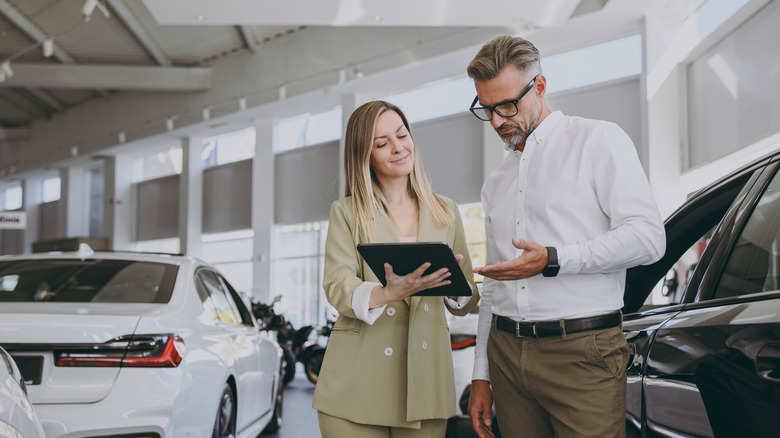 Car salesperson showing details to a customer