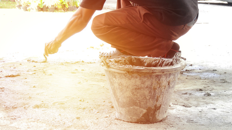 Person using a trowel to spread mixed concrete