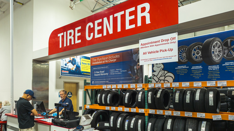 A Costco tire center display with tires stacked next to each other and a person maning the cash register.
