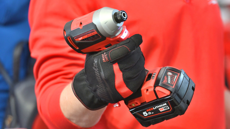 A person holding a Milwaukee impact driver.