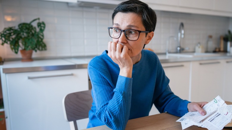 Woman contemplating with receipts in hand