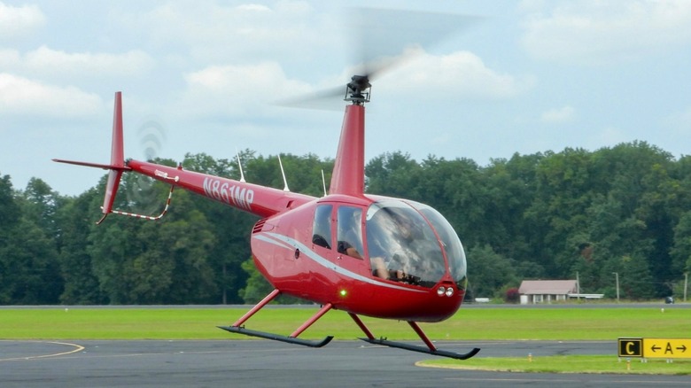 A Robinson R-44 helicopter hover taxiing in an airport