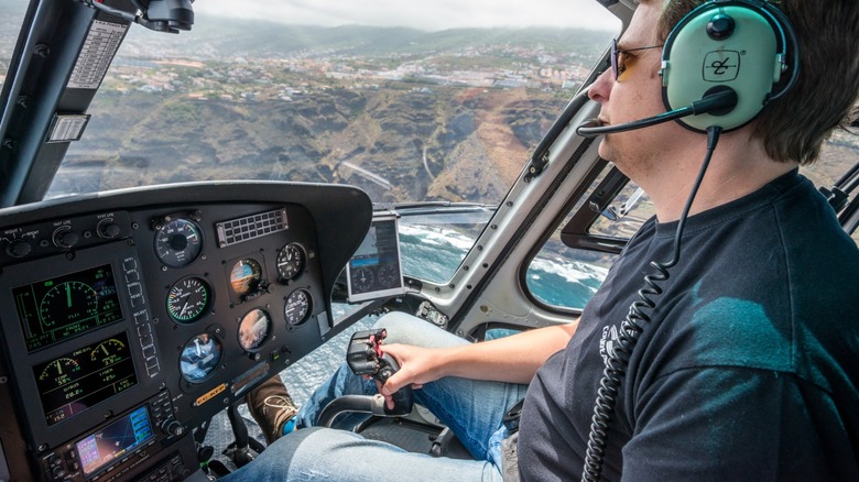 a helicopter pilot flying a chopper along the coast