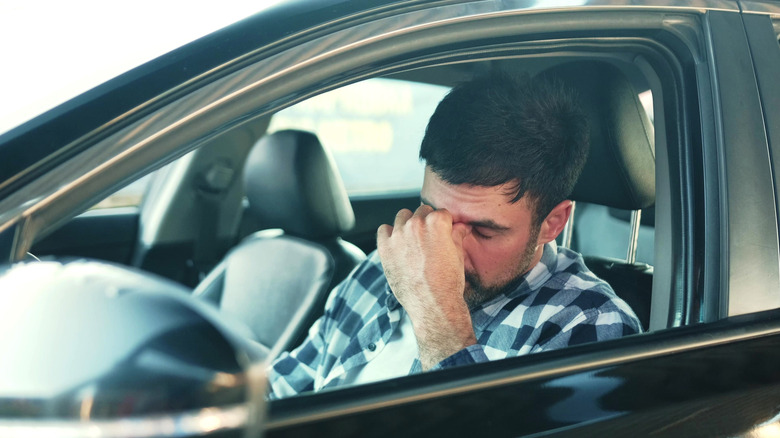 An image of a young man being frustrated behind the wheel of a vehicle.