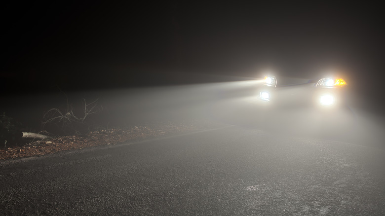 A car with headlights and fog lights turned on in the dark