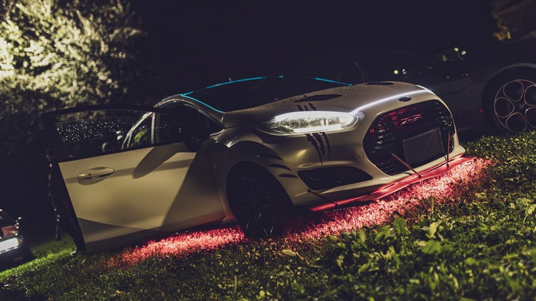 A modified Ford Fiesta ST displaying magenta underglow, front 3/4 view