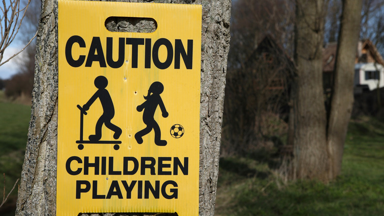 A yellow sign attached to a tree cautioning that children are at play in the area