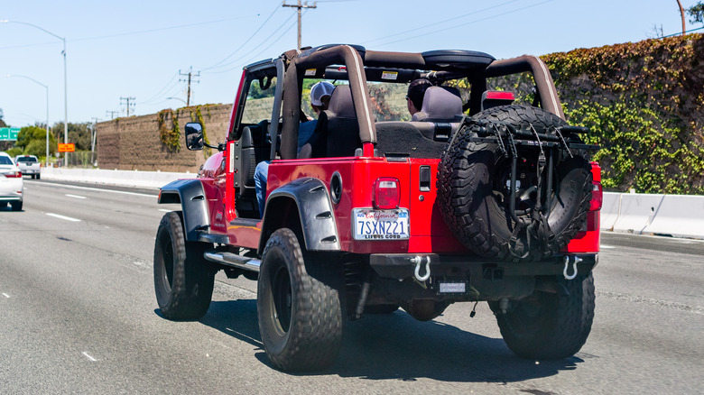 driving a red Jeep Wrangler on the highway with no doors
