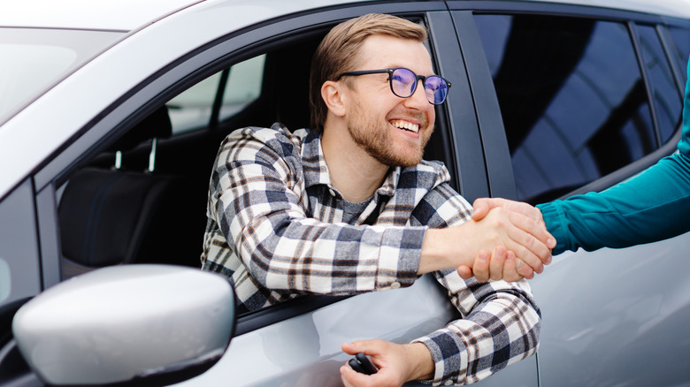 A man in a car shaking hands