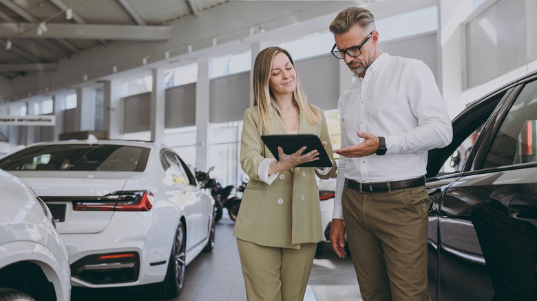 Man and woman at a car dealership drawing up a contract