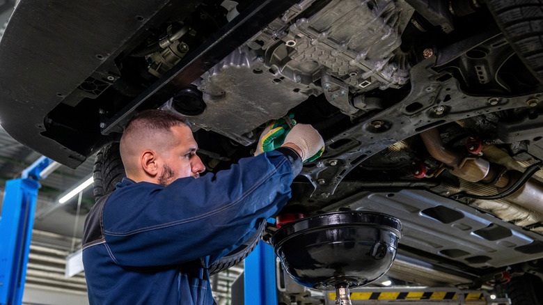 Mechanic draining the old oil from an engine