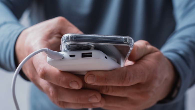 A person holding a phone and power bank