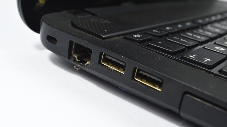 A close up of two USB ports on the side of a black laptop, plus an ethernet port.
