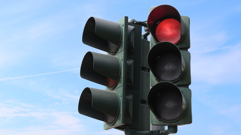 Red traffic light against blue sky