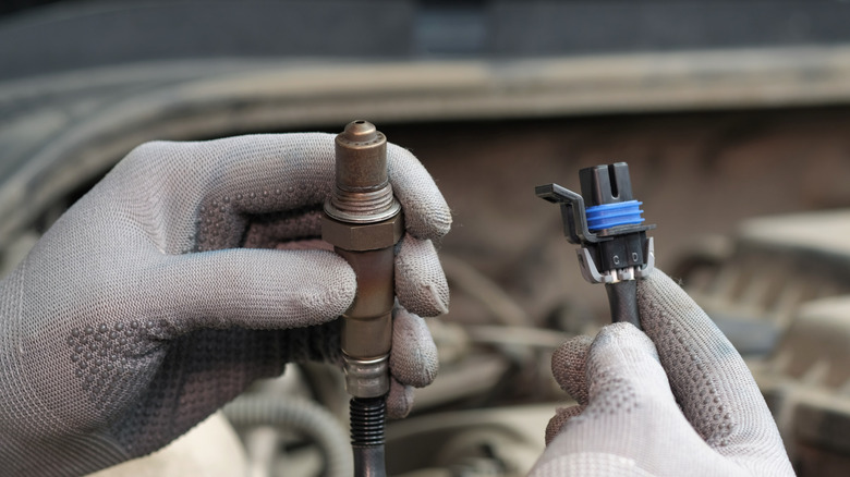 A person holding an automotive oxygen (o2) sensor