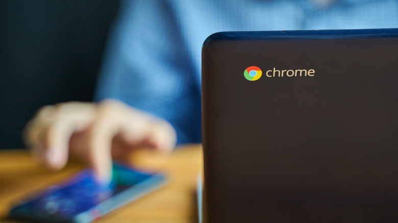 Person using a Chromebook and smartphone