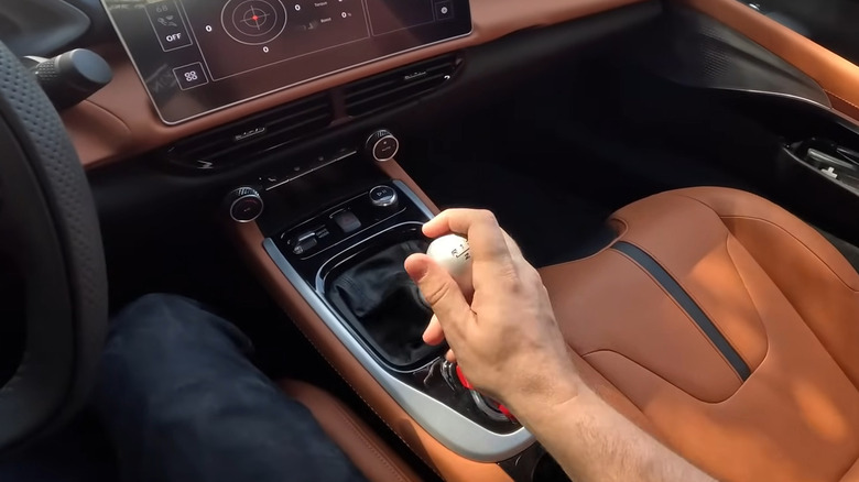 A driver holding the shifter in a manual transmission car