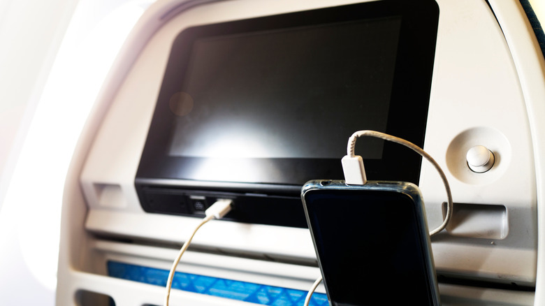 Mobile phone charging behind a seat on a plane