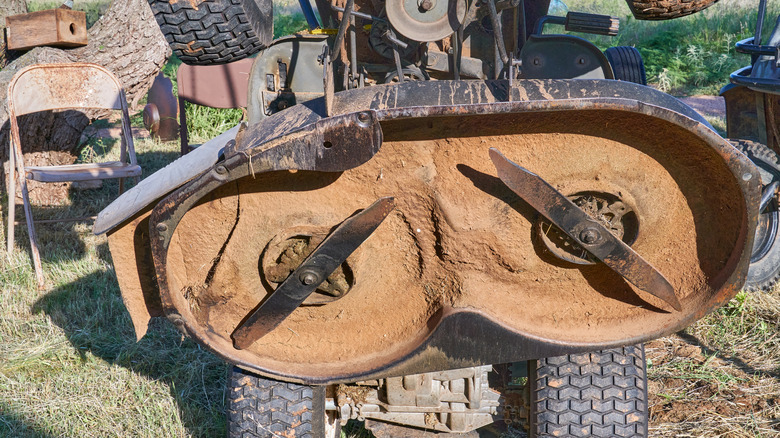 Dirty mower deck blades on the underside of a riding mower