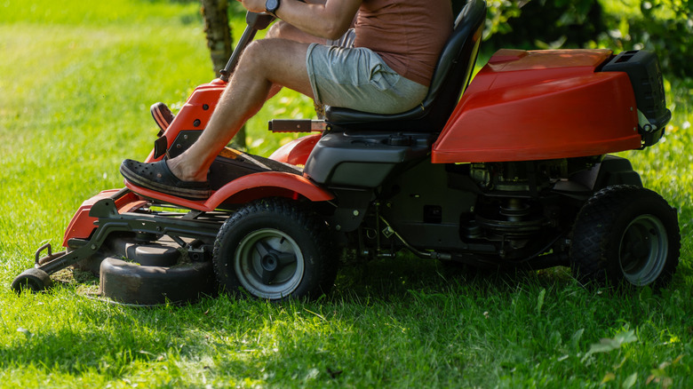 A person mowing the lawn with a riding mower