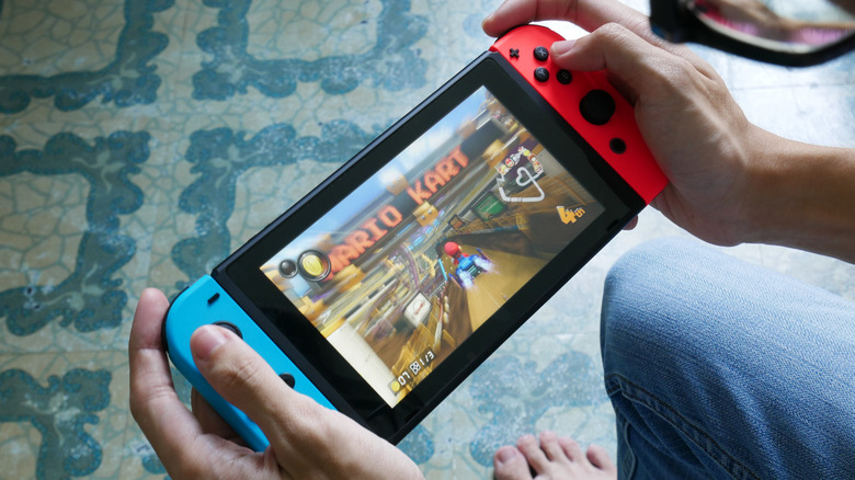A person holding the Nintendo Switch 2 in hand playing the Mario Kart video game.