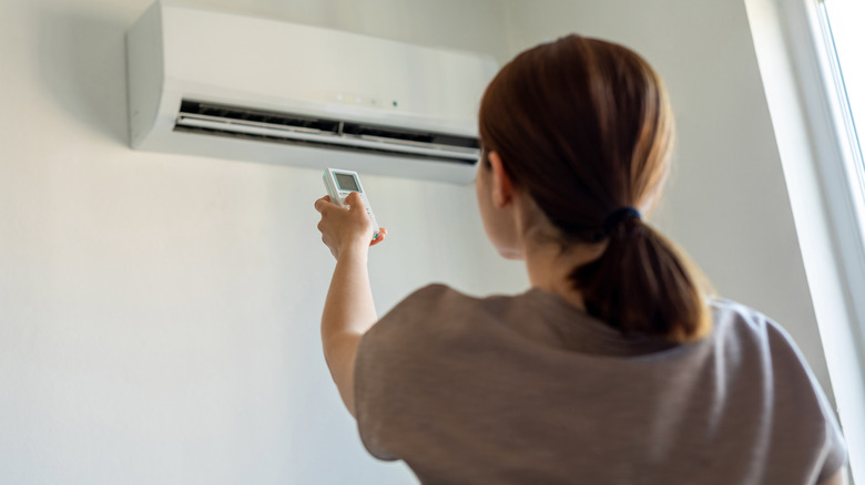 woman turning on central air conditioner in home