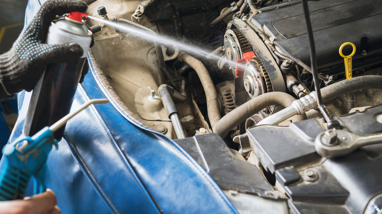 Mechanic spraying solution from can on car belt
