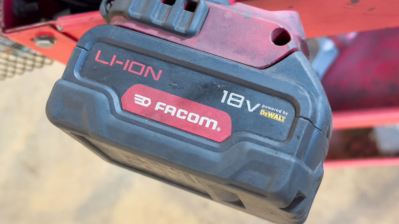 A dirty lithium-ion tool battery connected to a tool.