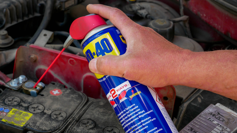 Mechanic cleaning battery terminals with WD-40