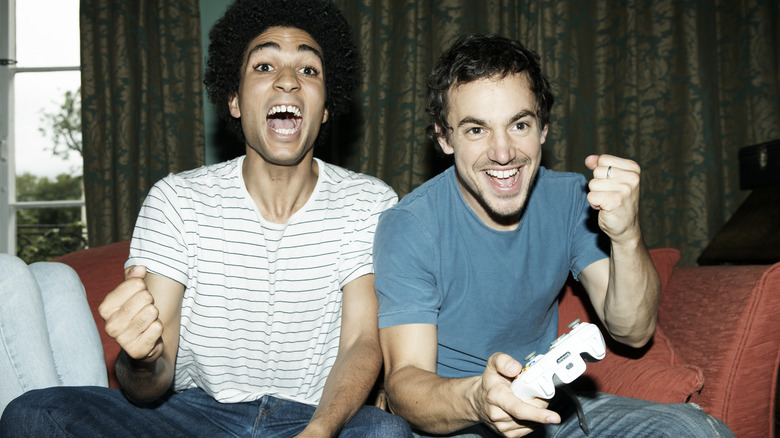 Two Men Playing Xbox While Sitting On A Sofa