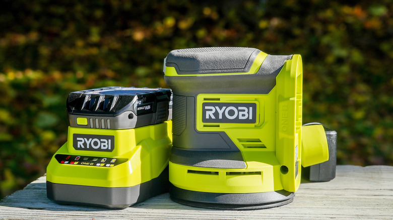 Ryobi orbital sander and battery charger on an outdoor table