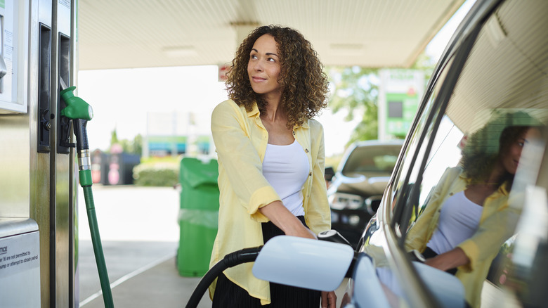 A person looking at the gas pump and fueling up their car