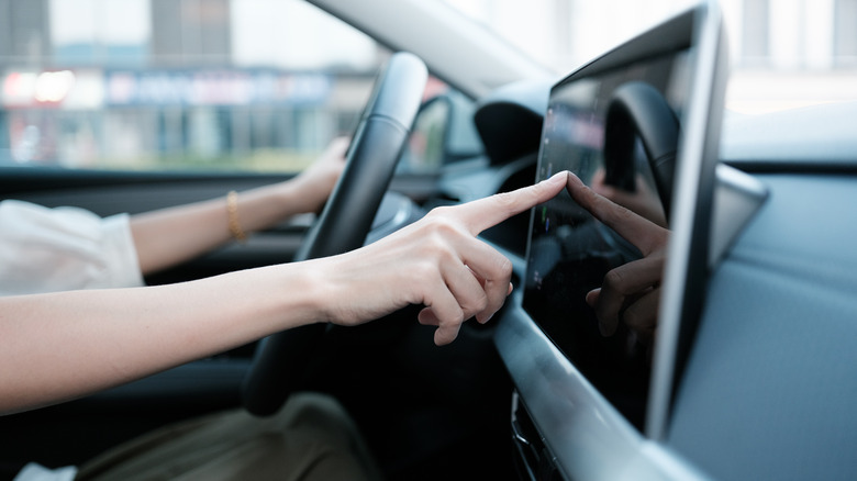 A person touching their car's front screen.