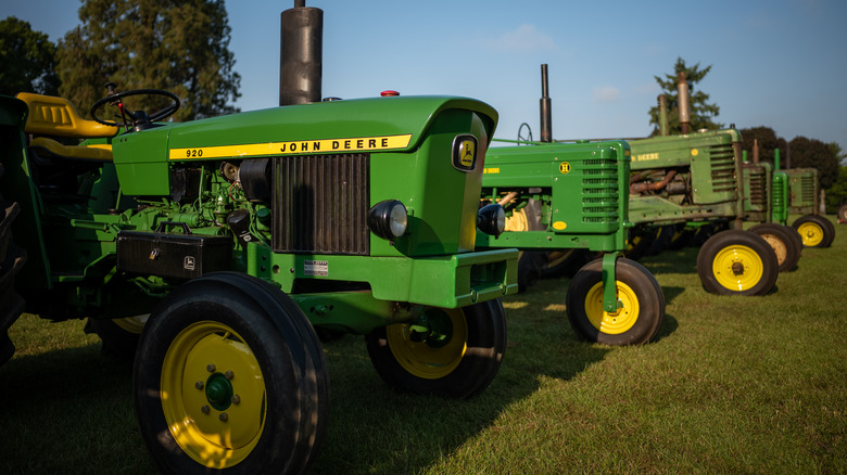 Several John Deere tractors lined up on grass.