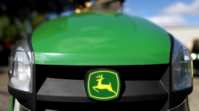 The front of a John Deere riding lawn mower with its leaping-deer logo in the center