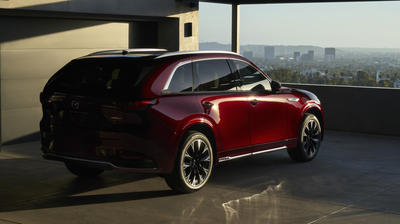 Rear 3/4 view of red Mazda CX-90 parked in parking garage.