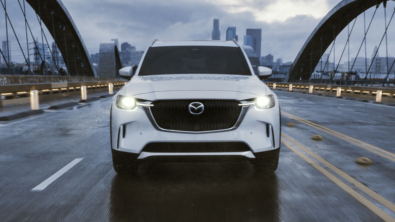 Front view of white Mazda CX-90 driving on bridge.
