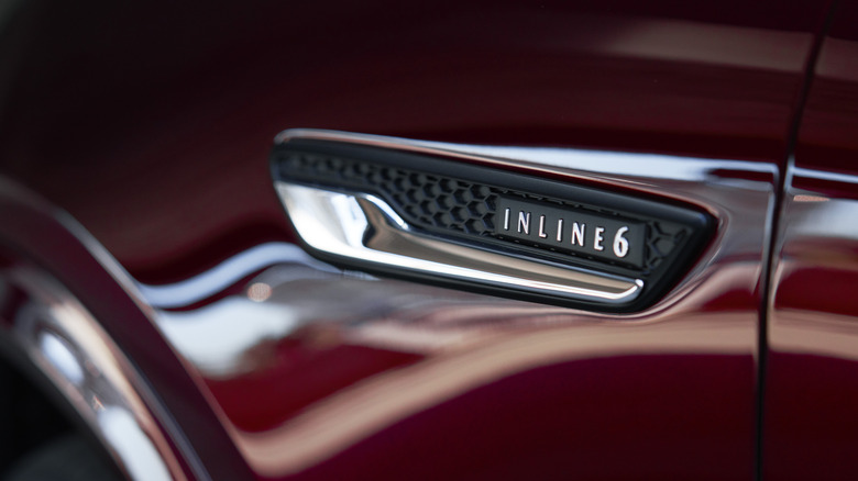 Close-up of "Inline 6" badge on red Mazda CX-90 fender.