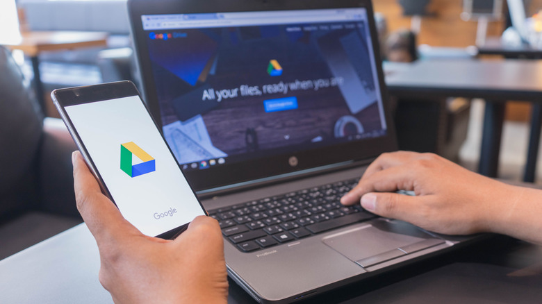 Hands using Google Drive on phone and laptop