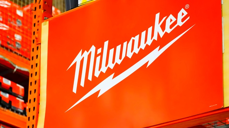 Sign on shelf with Milwaukee brand name, red shelved tool boxes in background