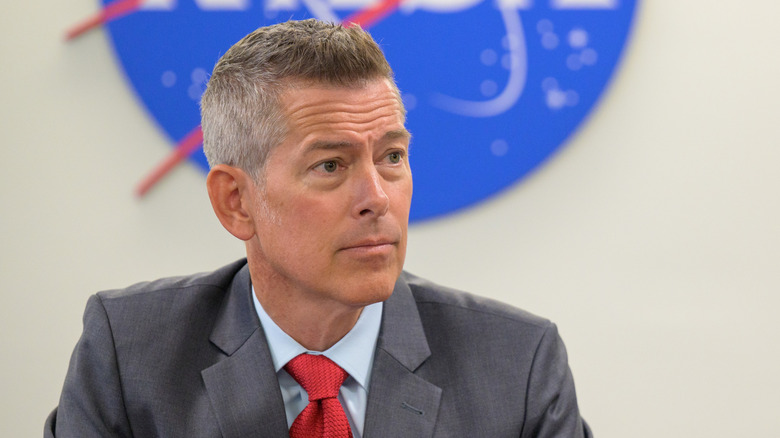 Interim NASA Administrator Sean Duffy sits before a NASA logo.