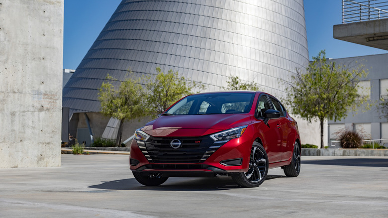 2025 Nissan Versa, front-view, parked on concrete road with industrial buildings in background