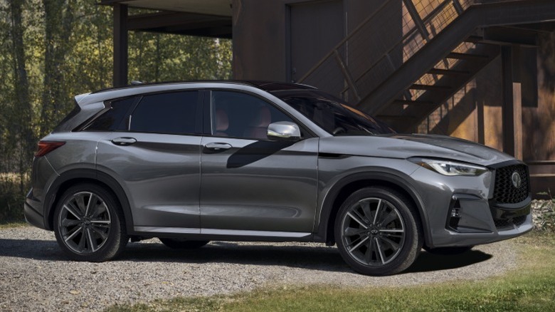 A gray 2025 Infiniti QX50 parked on gravel next to a building