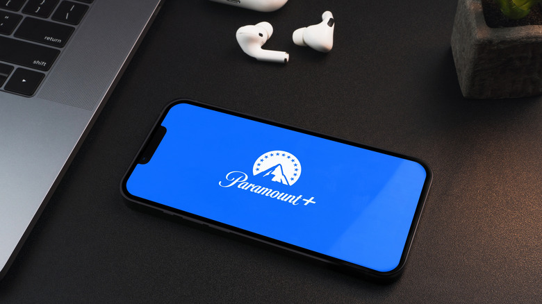 Phone with Paramount Plus logo next to laptop and headphones