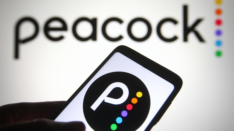 person holding phone in front of Peacock logo