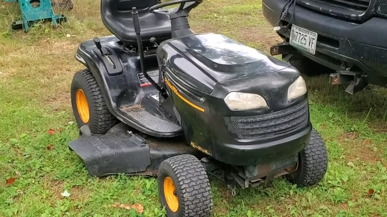 A Poulan Pro riding lawn mower beside a truck
