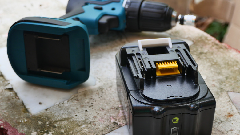 A battery and a cordless screwdriver sit side by side.