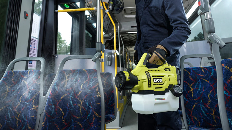 man cleaning inside of bus with sprayer